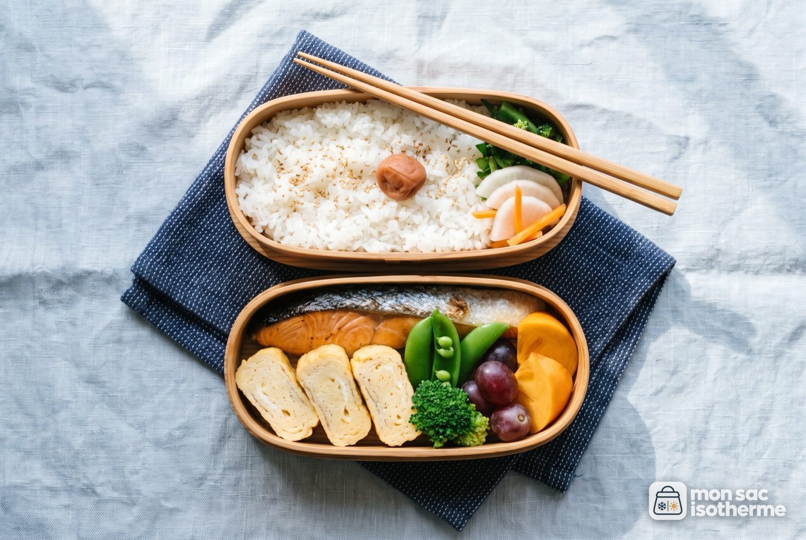 Bento japonais avec riz, saumon grillé, omelette roulée, légumes et fruits